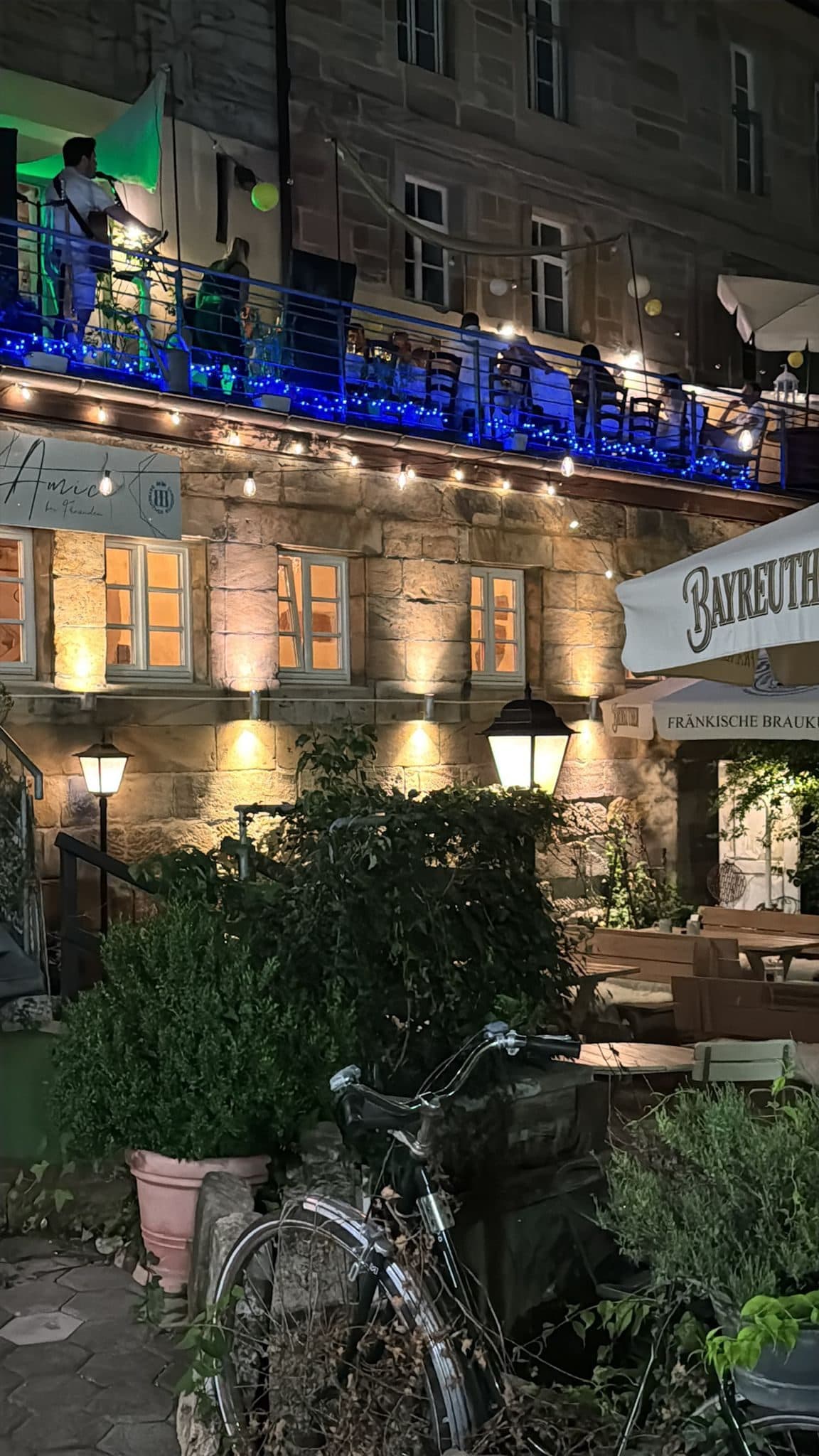Die Trattoria Amici bei Nacht — beleuchtete Fassade und Live-Musik auf der Terrasse